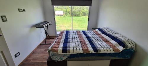 ein Schlafzimmer mit einem Bett mit einer Decke und einem Fenster in der Unterkunft Casaquinta las liebres in Villars