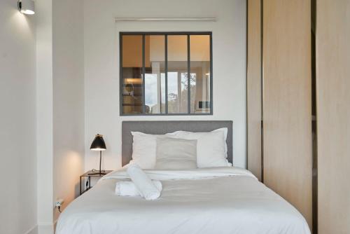 une chambre avec un grand lit avec des oreillers blancs dans l'établissement Charming and quiet apartment on the main boulevard, à La Madeleine