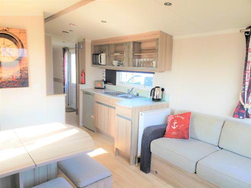 a living room with a couch and a kitchen in a caravan at Sea Break, Perran Sands, Perranporth in Perranporth
