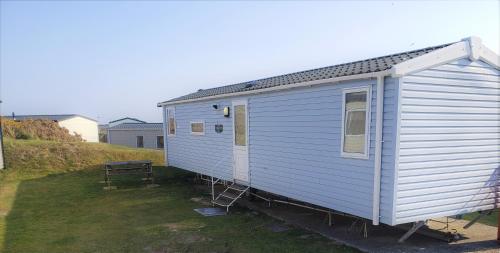 a blue tiny house sitting in a yard at Sea Break, Perran Sands, Perranporth in Perranporth