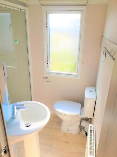 a bathroom with a toilet and a sink and a window at Sea Break, Perran Sands, Perranporth in Perranporth