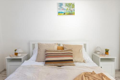 a bedroom with a white bed with two night stands at Malomvölgyi Vendégház in Balatonalmádi