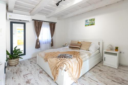 a white bedroom with a bed and a window at Malomvölgyi Vendégház in Balatonalmádi