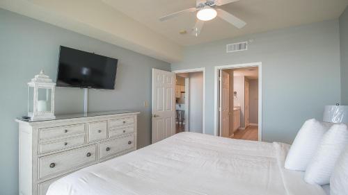 a bedroom with a white bed and a flat screen tv at Legacy I 407 in Gulfport