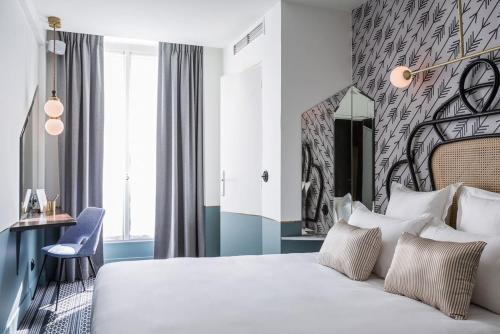 a bedroom with a large white bed and a desk at Hotel Panache in Paris