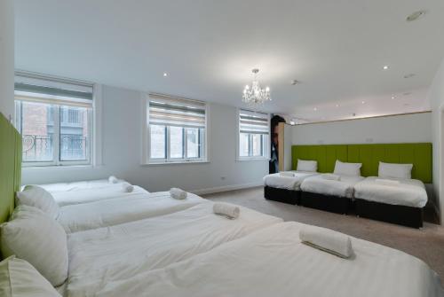 a bedroom with four beds and a chandelier at Temple Court Cavern Quarter Apartments by Happy Days in Liverpool