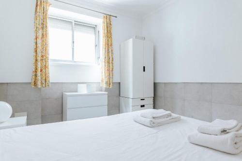 ein Schlafzimmer mit einem weißen Bett mit zwei Handtüchern darauf in der Unterkunft Lisboa - Moscavide, Parque das Nações Apartment in Lissabon