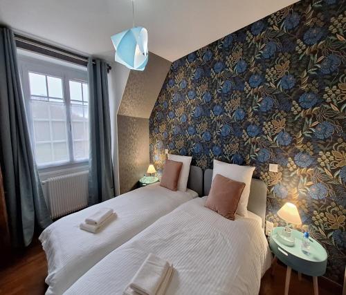 1 dormitorio con 2 camas y pared con papel pintado con motivos florales en La Jacquerie en Baye