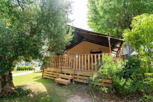 a cabin with a porch and benches in a yard at Sivinos Camping Boutique in Manerba del Garda