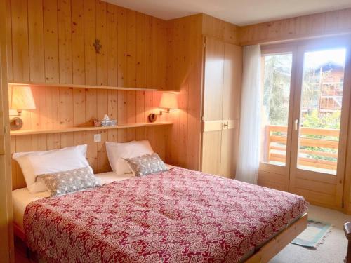 a bedroom with a bed with a red blanket and a window at Amadeus 132 in Verbier