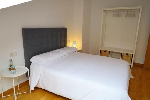 een slaapkamer met een groot wit bed en een tafel bij 33 Pasos Catedral 3 in León