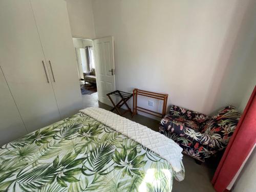 een kleine slaapkamer met een bed en een stoel bij The Stables, Central Garden Cottage in Howick in Howick