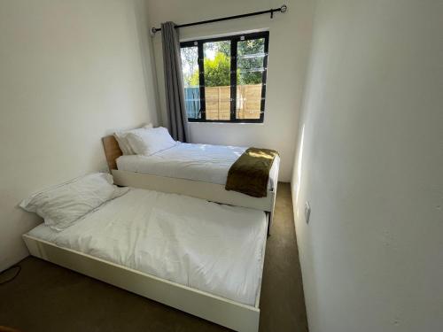 a small room with two beds and a window at The Stables, Central Garden Cottage in Howick in Howick