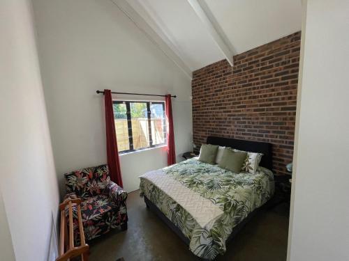 a bedroom with a bed and a brick wall at The Stables, Central Garden Cottage in Howick in Howick