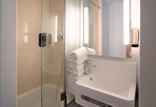 ein weißes Bad mit einem Waschbecken und einer Dusche in der Unterkunft B&B HOTEL Dreux Centre in Dreux