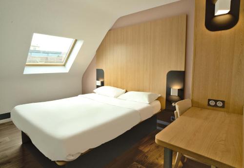 - une chambre avec un grand lit blanc et une table dans l'établissement B&B HOTEL Dreux Centre, à Dreux