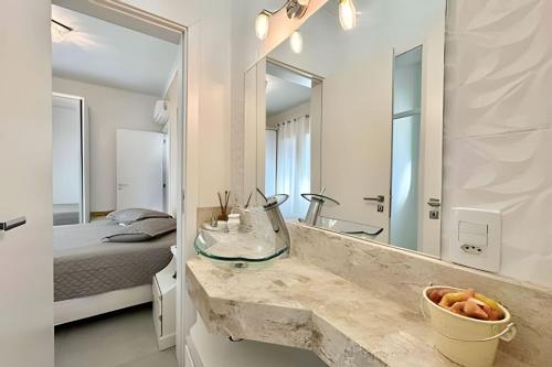 ein Badezimmer mit Waschbecken und Spiegel und einem Bett in der Unterkunft Casa 4 Suítes com piscina Fundos Lago-Ilhas Resort in Capão da Canoa