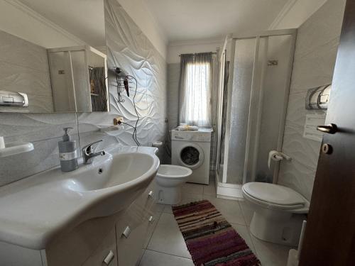 a white bathroom with a sink and a toilet at Perriera House in Sciacca