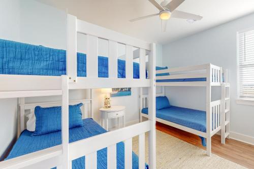 a bedroom with two bunk beds and a ceiling fan at Sunset Bay in Galveston