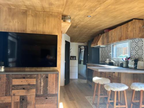 a kitchen with a large flat screen tv and stools at Chalet at Ski Lift (Gsteig b. Gstaad) in Gsteig