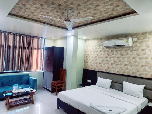 1 dormitorio con 1 cama y 1 sofá azul en Hotel Vallabh Vilas en Hoshangābād