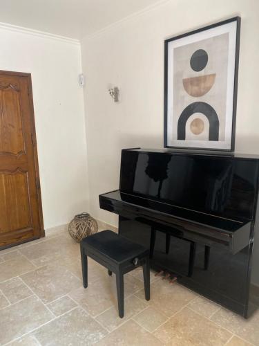 un piano noir avec un tabouret et une photo sur le mur dans l'établissement BASTIDE VALPIERRE, à Martigues