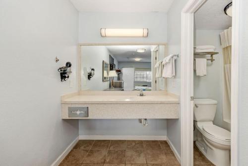 a bathroom with a sink and a toilet and a mirror at Grove City Travel Inn in Grove City
