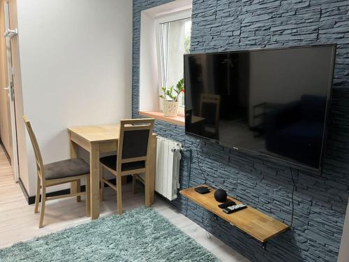 un salon avec une table et une télévision sur un mur en briques dans l'établissement Wola Studio Flat near Progresia, à Varsovie