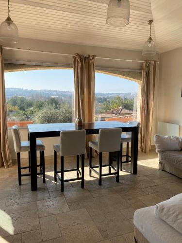 une salle à manger avec une table, des chaises et une grande fenêtre dans l'établissement BASTIDE VALPIERRE, à Martigues