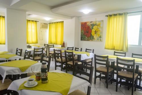 a dining room with tables and chairs with yellow curtains at Hotel Lacala in Florianópolis