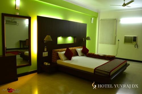 a bedroom with a bed in a green room at Hotel Yuvraj Dx in Pipra Dewās