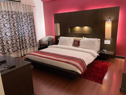 a bedroom with a large bed with a red wall at Hotel Yuvraj Dx in Pipra Dewās