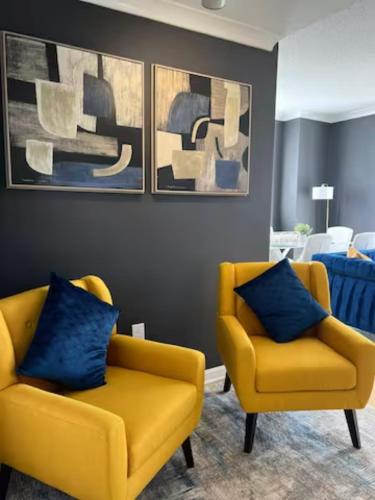 a living room with two yellow chairs and paintings at Elegant King Suite Metro DC in Arlington