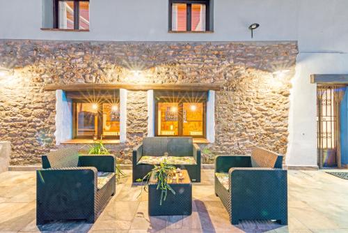 a patio with chairs and a table and a stone wall at Luxe Mediterranean Masia BBQ Pool Chillout in Mas de Catalá