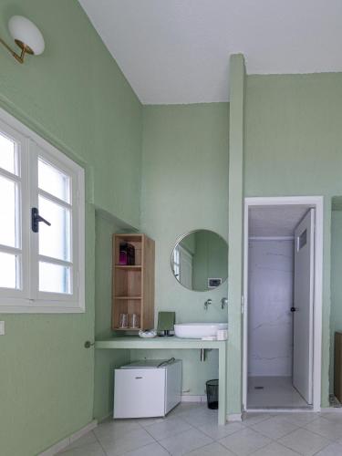 a green bathroom with a sink and a mirror at Triton Authentic Cretan Hotel in Tsoútsouros