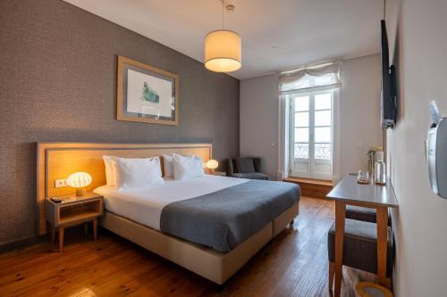 a hotel room with a bed and a window at Santa Catarina FLH Suites in Porto