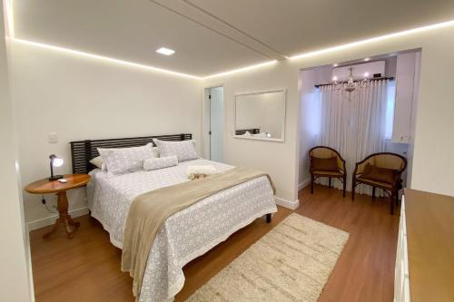 een slaapkamer met een bed en een tafel en stoelen bij Locar-in Gramado- Jardim Europa in Gramado
