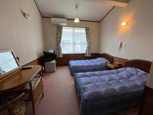 ein Hotelzimmer mit 2 Betten und einem Schreibtisch in der Unterkunft ペンションパティオハウスリーフ 