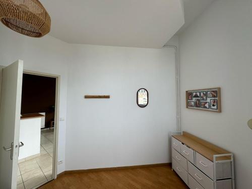 a room with a white wall and a mirror at Résidence des Berges de l’Aisne in Soissons