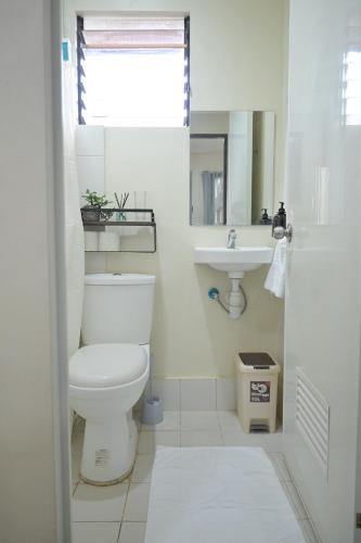biała łazienka z toaletą i umywalką w obiekcie Hyacinth by Elle's Place near Dumaguete Airport w mieście Dumaguete