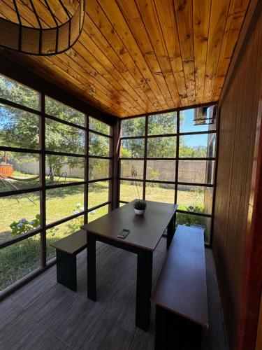 a room with a table and a bench and windows at Hostal Treile in Pucón