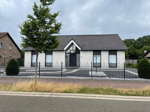 a white house with a fence in front of it at Vakantiewoning Villa 35 in Maasmechelen