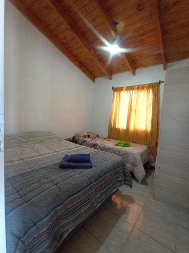 1 dormitorio con 2 camas en una habitación con techos de madera en Mia cabañas en El Calafate