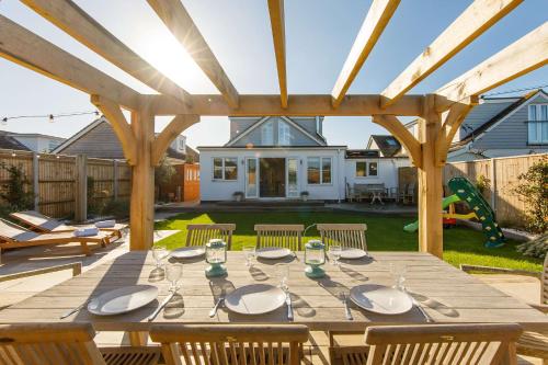 a wooden table in a backyard with a wooden pergola at 4BR Beach House sleeps 10 - 5 mins walk to the Sea in West Wittering