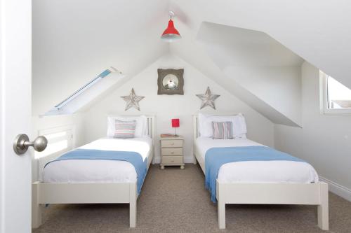 2 camas en un dormitorio del ático con paredes blancas en 4BR Beach House sleeps 10 - 5 mins walk to the Sea, en West Wittering