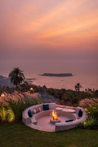 a fire pit in a yard with the ocean in the background at SaffronStays Mimosa Sunsets in Dapoli