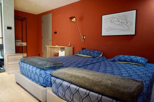 a bedroom with two beds and an orange wall at Silom Soi 3 Hip and funky apartment with rooftop view in Bangkok