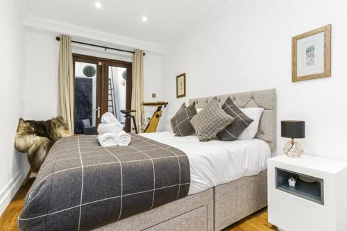 a bedroom with a bed with a gray blanket at Notting Hill 2BR Gem l Stylish Prime Apt in London