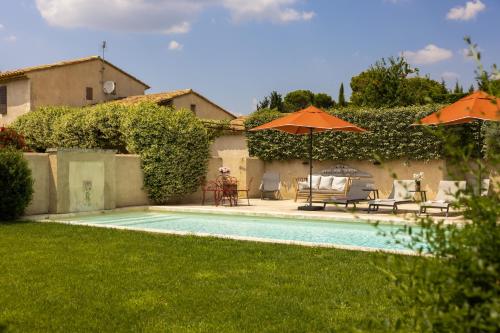 une piscine avec chaises et parasols dans une cour dans l'établissement Le Mas Paradou, 5 chambres, piscine privée, accès au village à pied, à Paradou