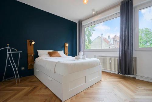 une chambre avec un lit blanc et une grande fenêtre dans l'établissement Lille République - 2ch très lumineux + Parking !, à Lille